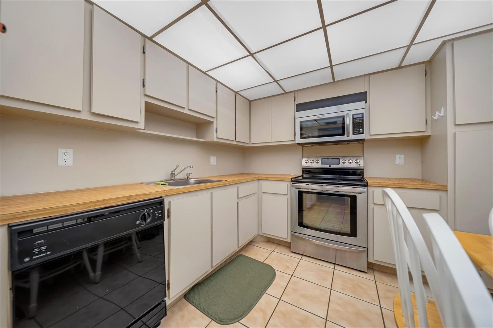 A kitchen features light-colored cabinets, wood countertops, stainless steel appliances, and a drop ceiling — 801 Cypress Boulevard # 107c, Pompano Beach FL 33069, POMPANO BEACH, FL
