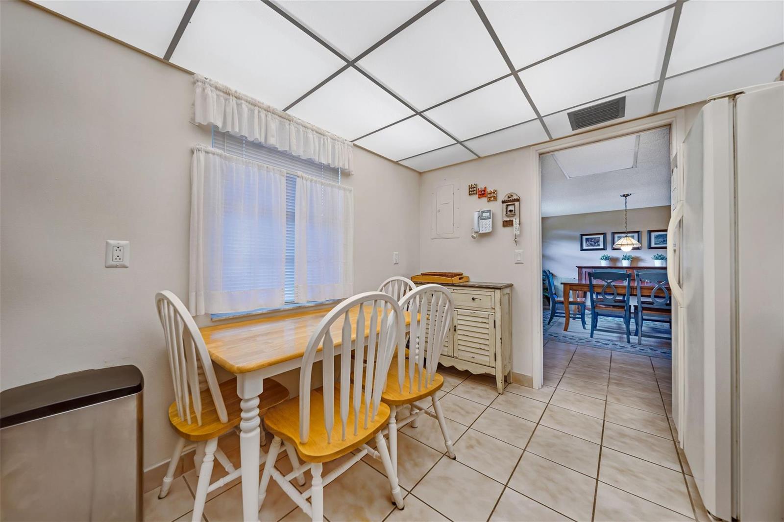 A kitchen dining area features a wooden table, four chairs, tiled floors, and a drop ceiling — 801 Cypress Boulevard # 107c, Pompano Beach FL 33069, POMPANO BEACH, FL