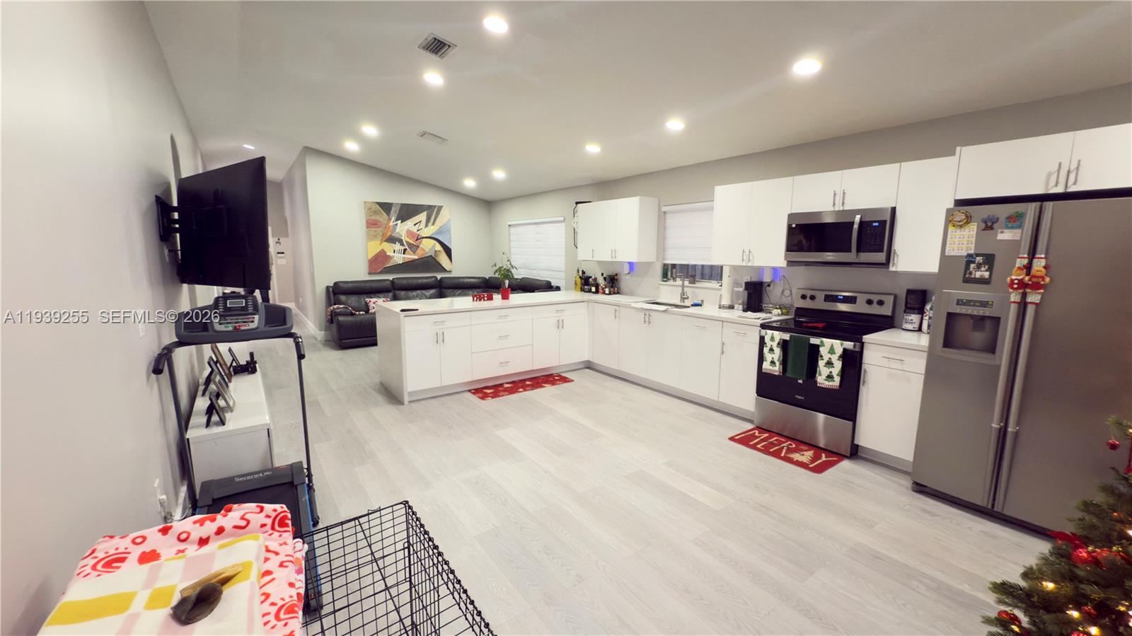 A modern open-concept kitchen features white cabinetry, stainless steel appliances, and light wood-look flooring — 2006 SE 14th Ct # 0, Homestead FL 33035, HOMESTEAD, FL