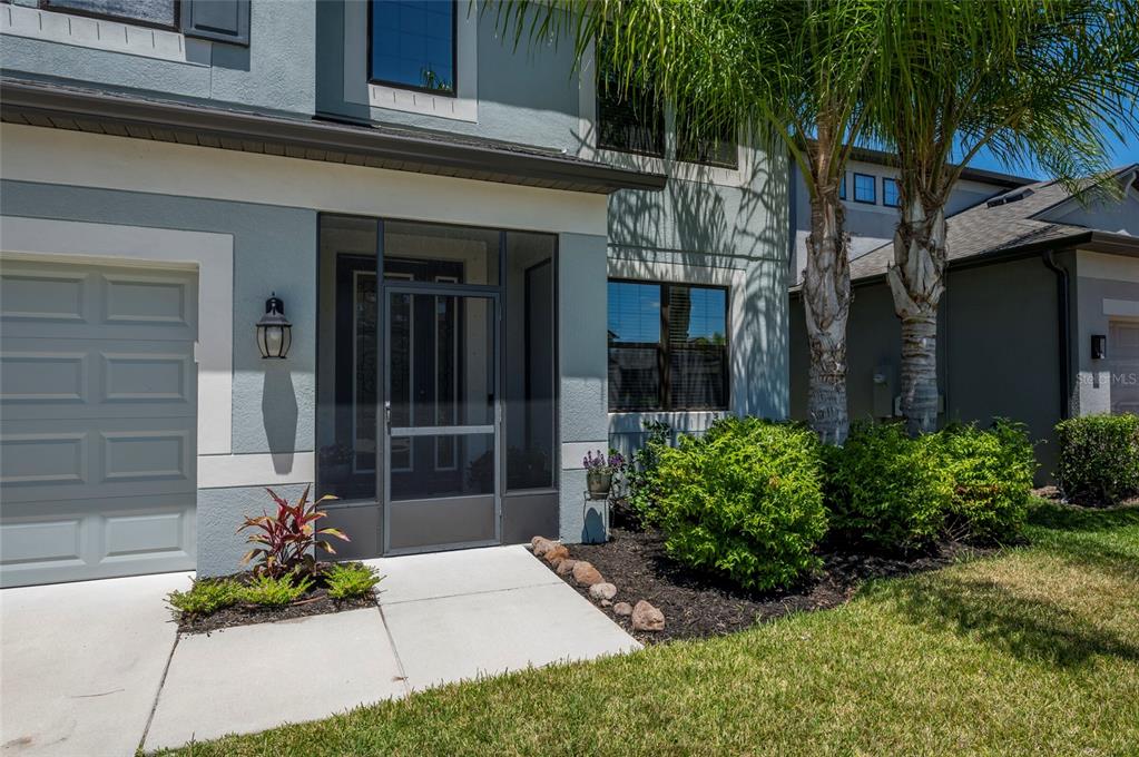 The exterior of a two-story home features a screened entryway, a garage, and landscaping — 11420 AMAPOLA BLOOM COURT, RIVERVIEW, FL