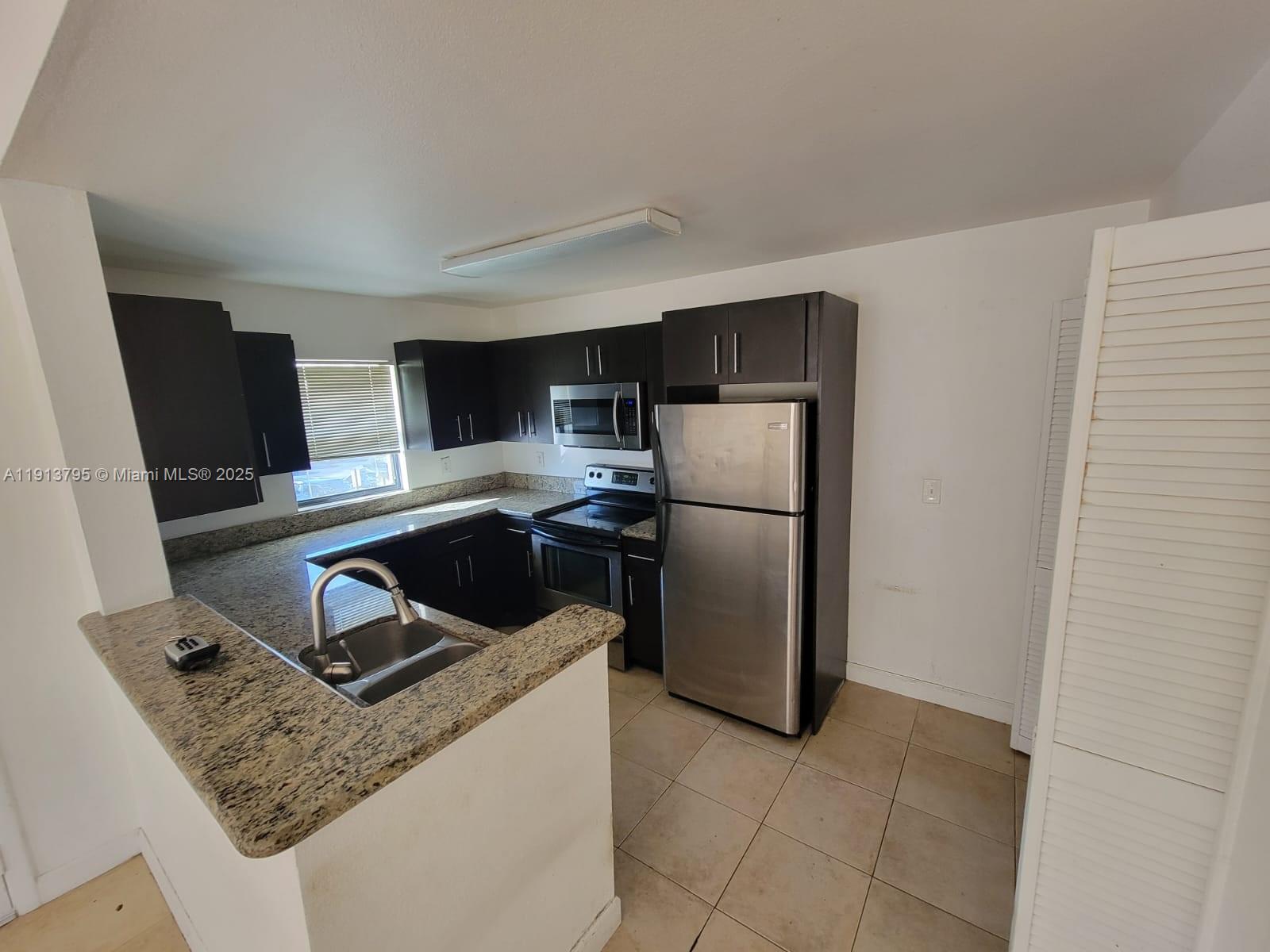 A kitchen features dark cabinets, granite countertops, stainless steel appliances, and beige tile flooring — 3992 NW 87th Ave # 3992, Sunrise FL 33351, SUNRISE, FL