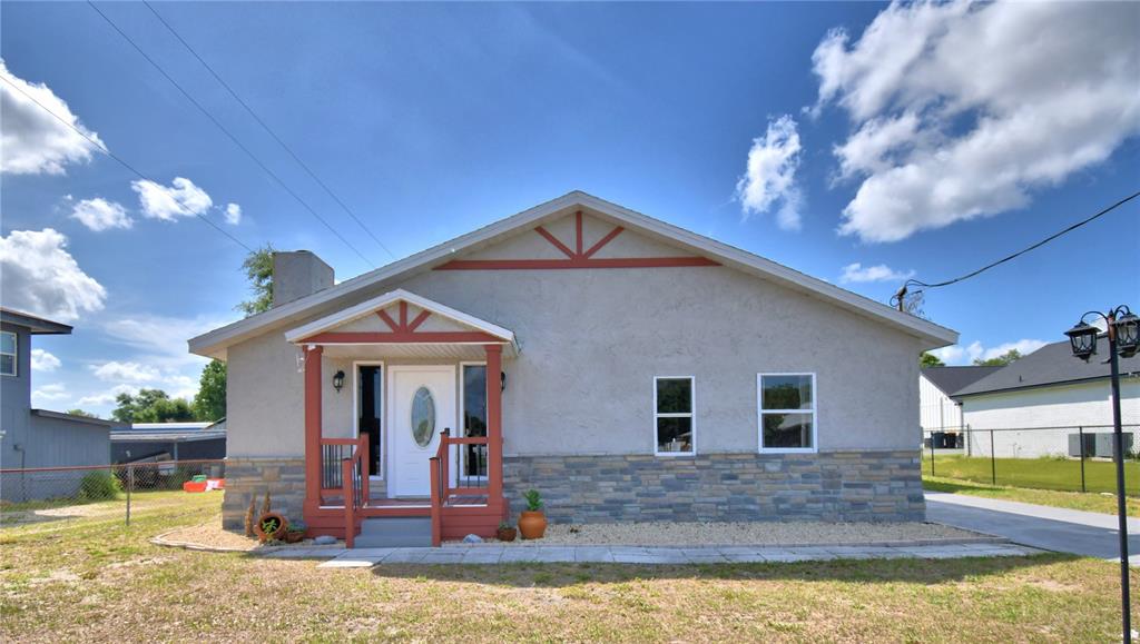 A single-story house with a stucco exterior, stone veneer base, and a covered front porch — 208 CENTER STREET, AUBURNDALE, FL