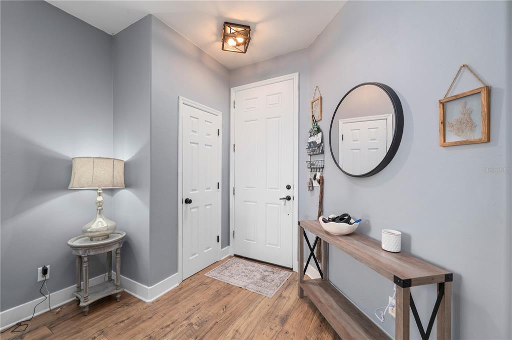 An entryway features gray walls, wood-look flooring, a white door, and a console table — 25538 PRADA DRIVE, PUNTA GORDA, FL