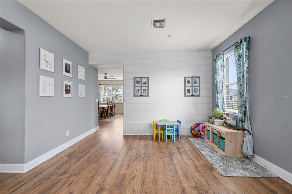 A playroom with wood-look flooring, gray walls, a white shiplap accent wall, and a window — 25538 PRADA DRIVE, PUNTA GORDA, FL