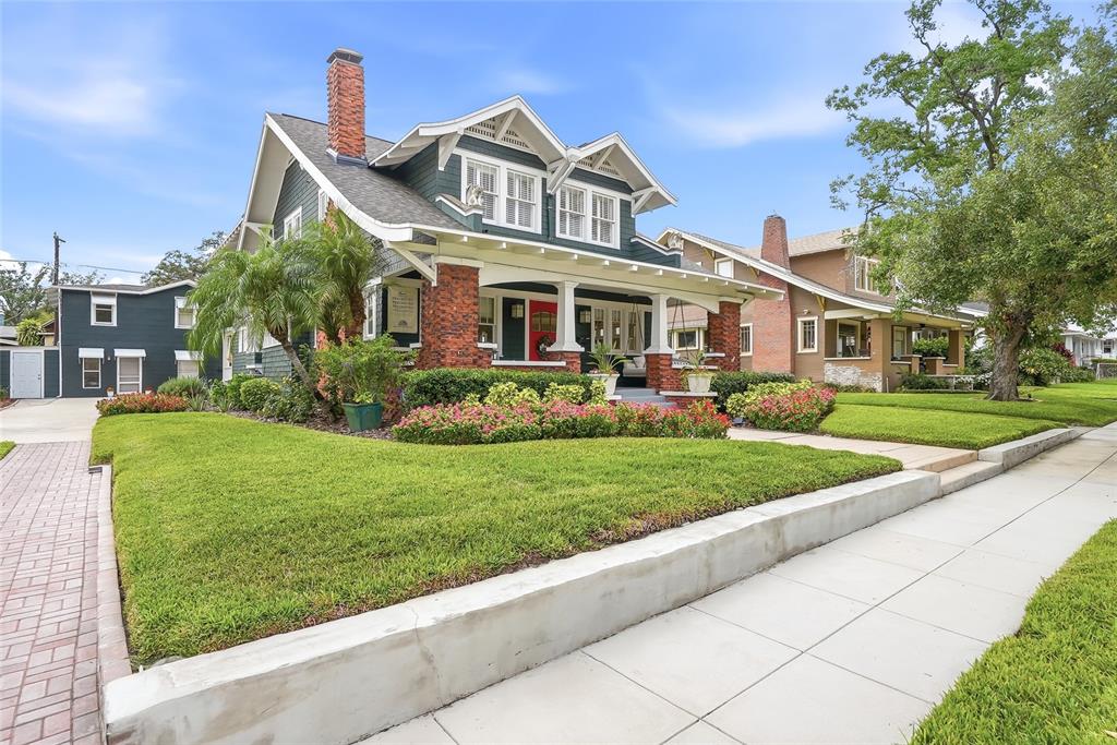 A two-story blue craftsman house with a brick chimney, front porch, and landscaped yard — 929 S OREGON AVENUE, TAMPA, FL