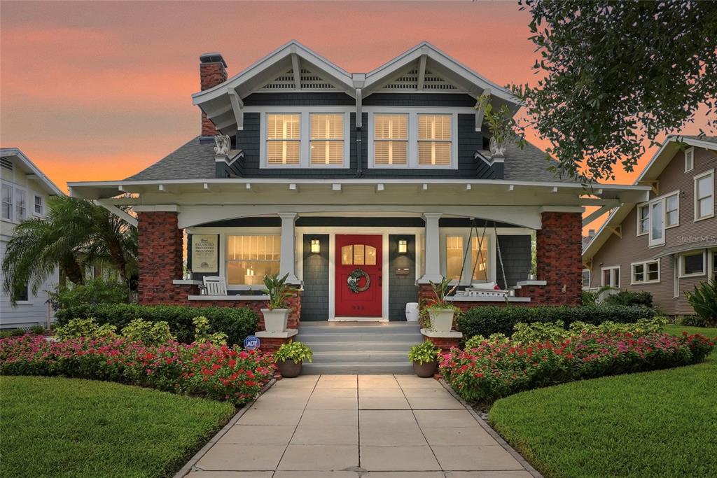 A front porch features a red door, brick columns, white planters, and a hanging swing — 929 S OREGON AVENUE, TAMPA, FL