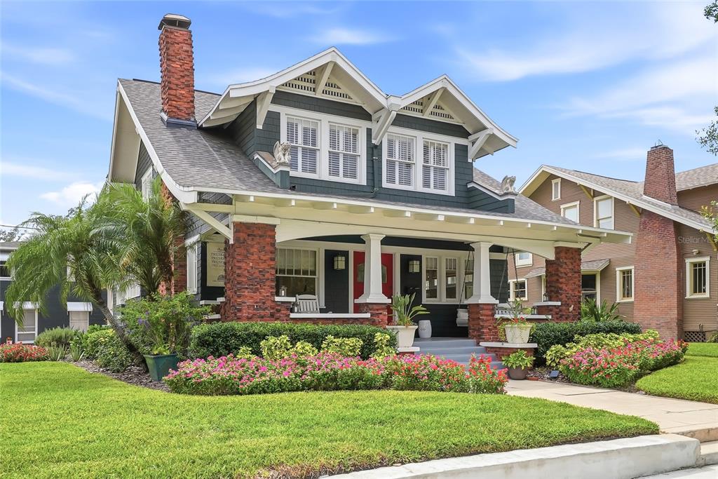 A two-story blue craftsman-style house features a brick porch, white trim, and landscaped gardens — 929 S OREGON AVENUE, TAMPA, FL