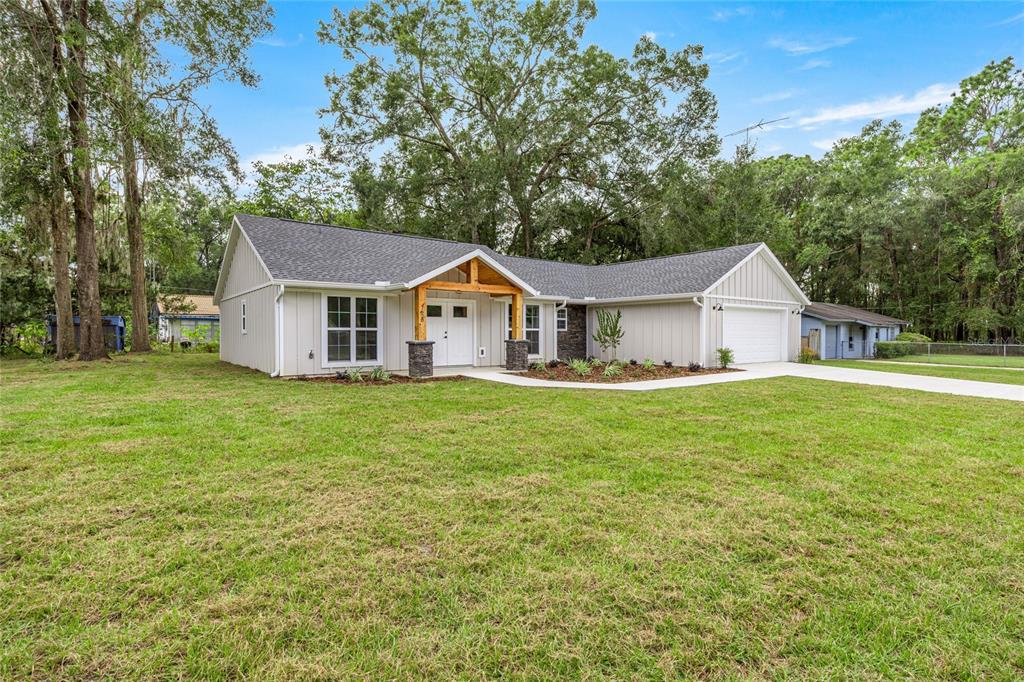 A single-story house with light gray vertical siding, a dark roof, and a wooden porch — 7620 SW 78TH PLACE, OCALA, FL