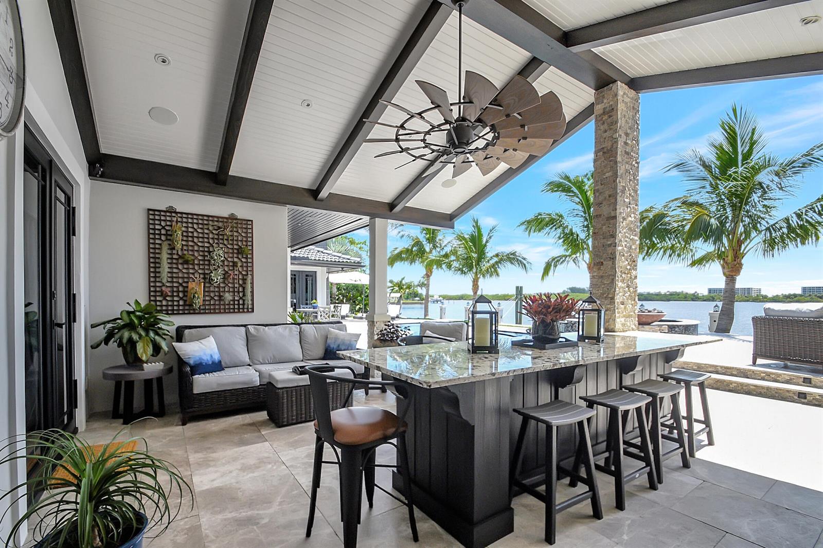 A covered outdoor patio features a stone-topped bar, seating area, and views of the water — 1 Duke Drive, FL 33460, FL