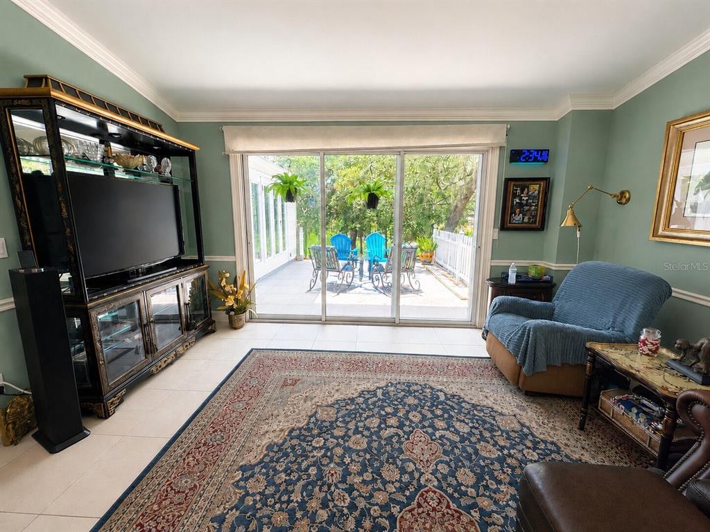 A living room with a large entertainment center, blue armchair, and sliding doors to a patio — 16363 SE 5TH STREET, SILVER SPRINGS, FL