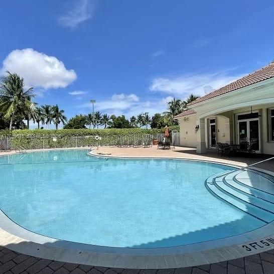 A swimming pool with steps sits in front of a building under a blue sky — 8014 Big Pine Way, Riviera Beach FL 33407, RIVIERA BEACH, FL