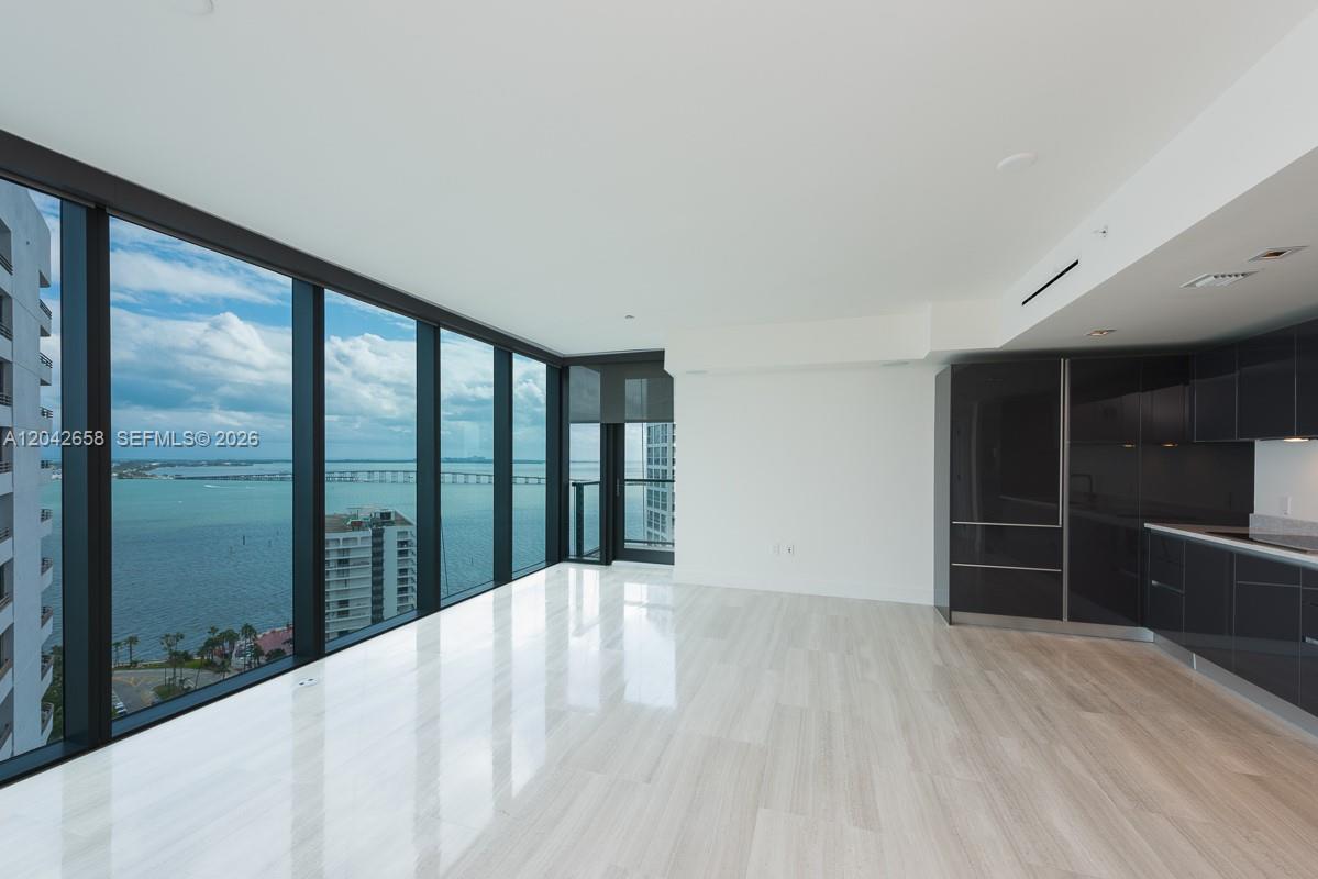 A modern living area features floor-to-ceiling windows, light wood flooring, and a dark kitchen — 1451 Brickell Ave # 2103, Miami FL 33131, MIAMI, FL