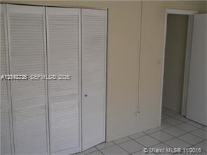 A room features white louvered closet doors, light-colored walls, and white tiled flooring — 9760 SW 184th St # 7C, Cutler Bay FL 33157, CUTLER BAY, FL