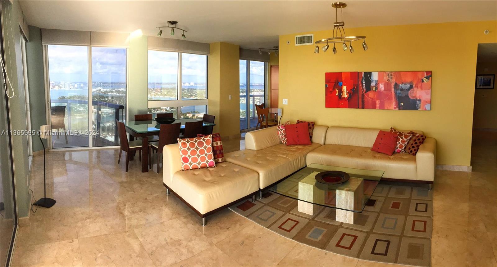 A living and dining area with beige tile floors, a sectional sofa, and floor-to-ceiling windows — 6365 COLLINS AV # 3407, Miami Beach FL 33141, MIAMI BEACH, FL