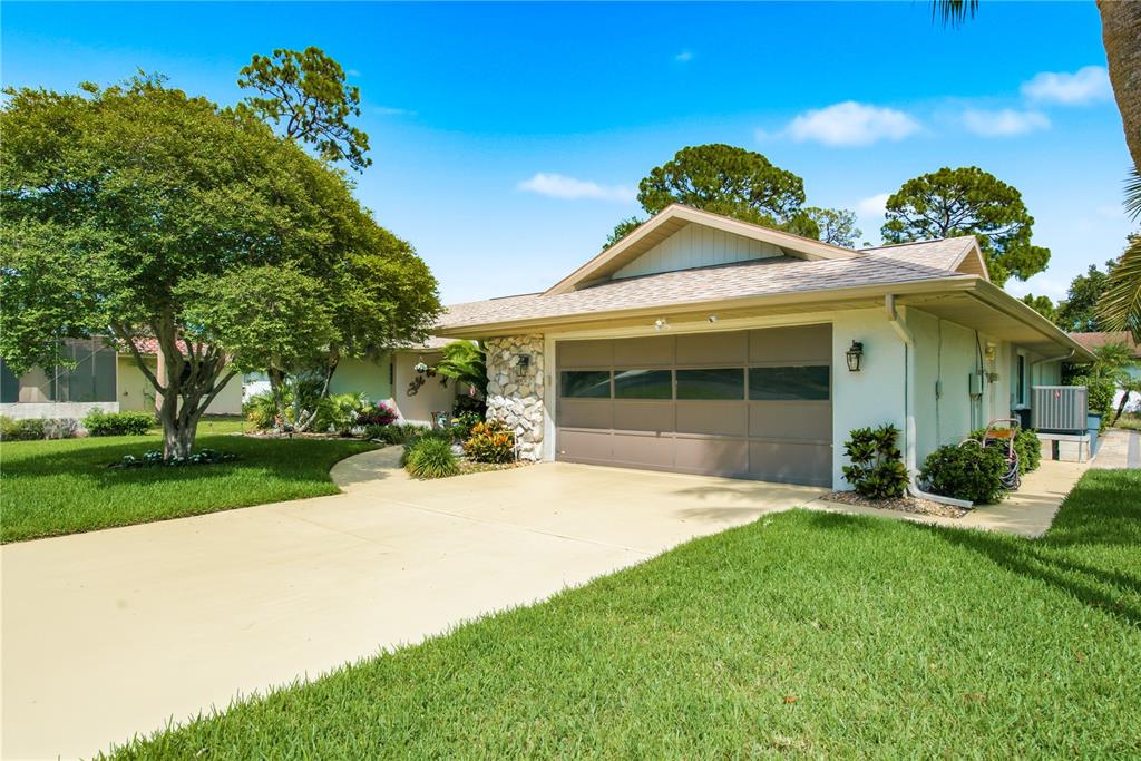 A single-story house with a large tree, stone accents, and a two-car garage — 5468 NIMITZ ROAD, NEW PORT RICHEY, FL