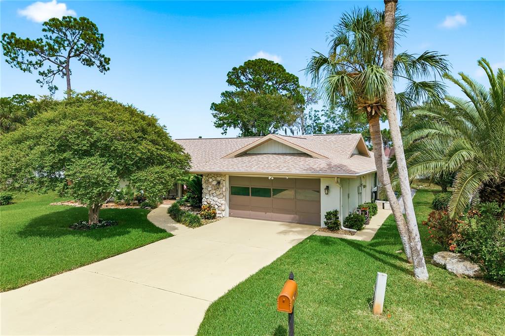A single-story house with a stone facade, a large front tree, and a concrete driveway — 5468 NIMITZ ROAD, NEW PORT RICHEY, FL