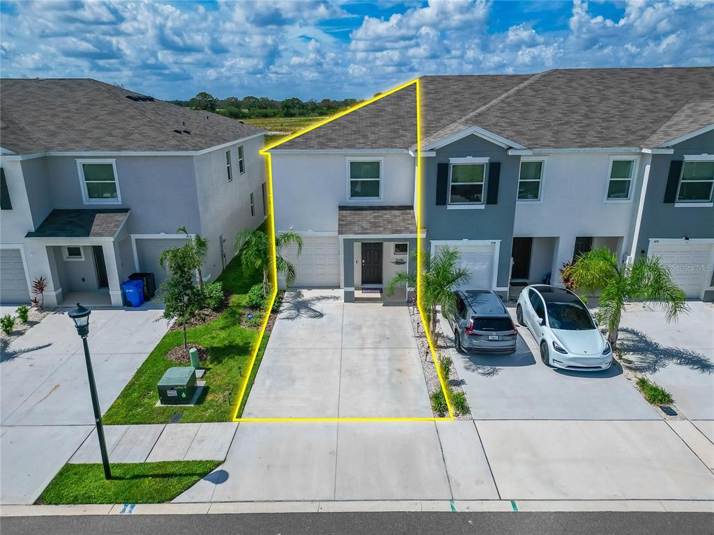 An aerial view shows a two-story townhouse with a concrete driveway and a yellow outline — 472 MANGROVE SHADE CIRCLE, APOLLO BEACH, FL