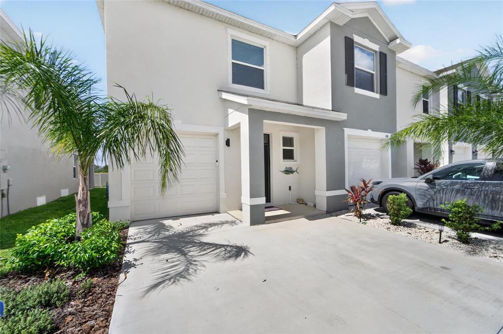 A two-story townhouse exterior features a white and gray facade with a single-car garage — 472 MANGROVE SHADE CIRCLE, APOLLO BEACH, FL