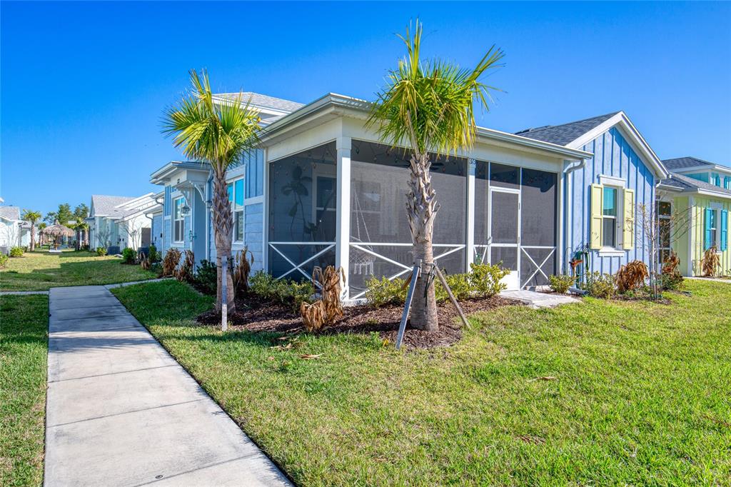 A light blue house features a screened-in porch and two palm trees in the front yard — 373 HANG LOOSE WAY, DAYTONA BEACH, FL