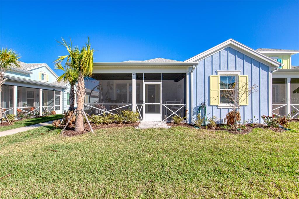 A light blue house with a screened-in front porch and yellow shutters under a clear sky — 373 HANG LOOSE WAY, DAYTONA BEACH, FL