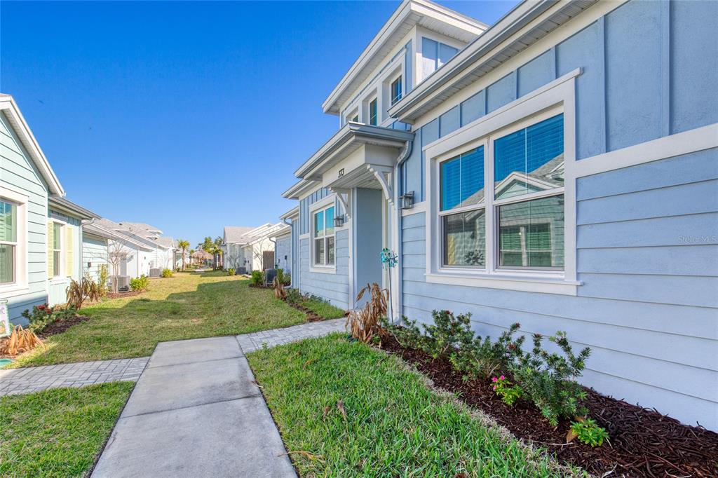 A light blue house with white trim and a concrete walkway on a sunny day — 373 HANG LOOSE WAY, DAYTONA BEACH, FL