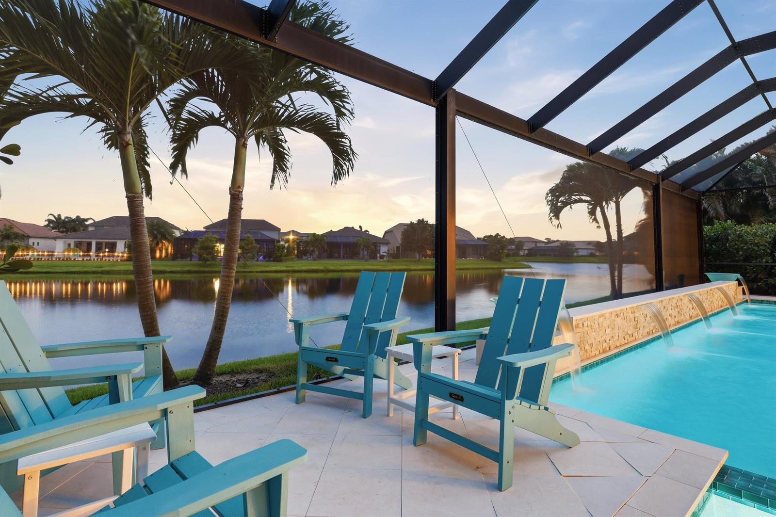 A screened-in patio features a swimming pool with water features and light blue Adirondack chairs — 134 Indigo River Point, Jupiter FL 33478, JUPITER, FL
