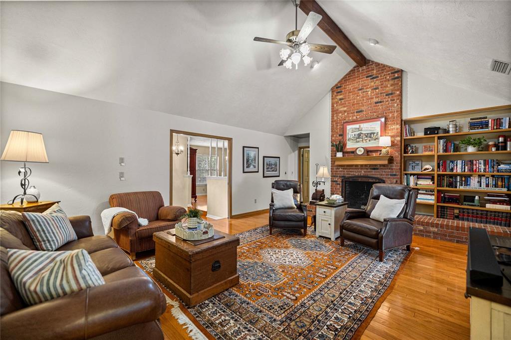 A living room features a vaulted ceiling, brick fireplace, built-in bookshelves, and hardwood floors — 2801 SE 14TH STREET, OCALA, FL