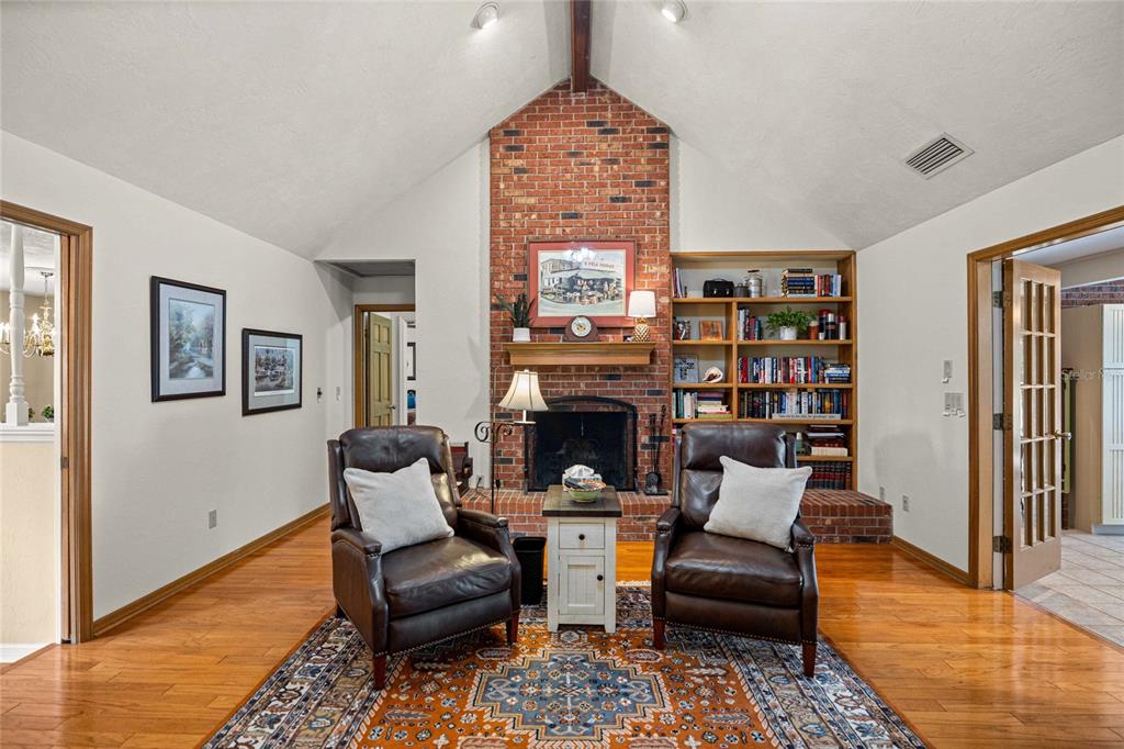 A living room features a brick fireplace, built-in bookshelves, two leather armchairs, and hardwood floors — 2801 SE 14TH STREET, OCALA, FL