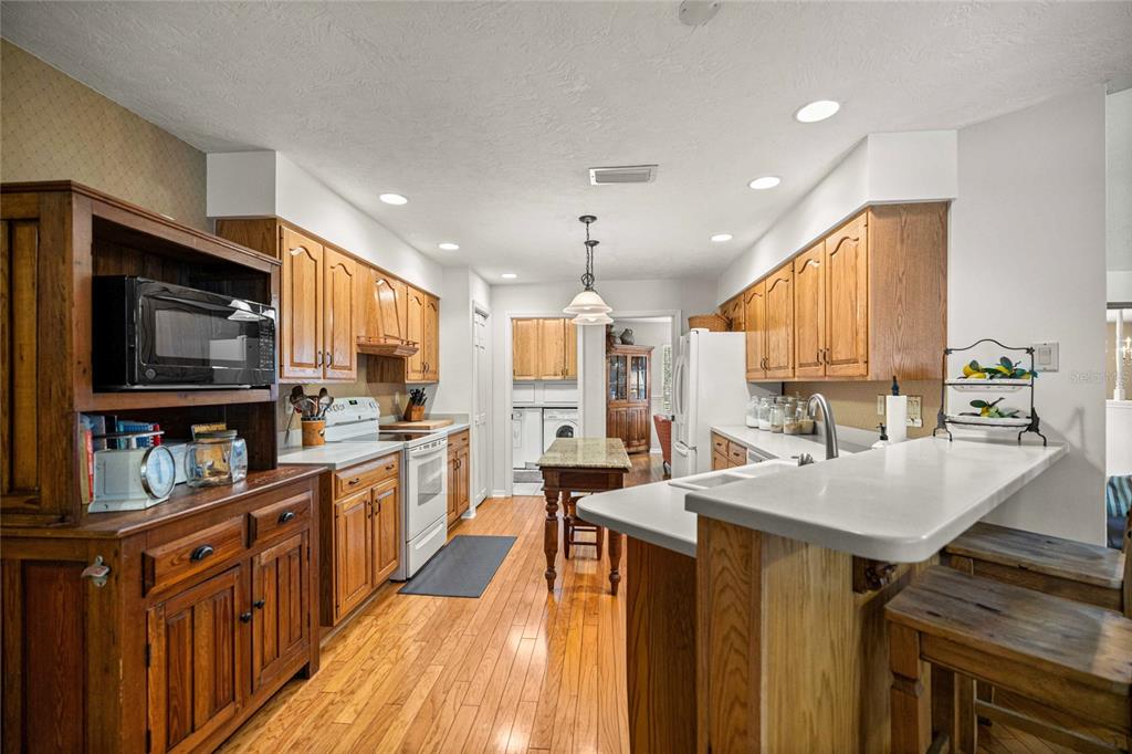 A kitchen with wood cabinets, a central island, and a breakfast bar with two stools — 2801 SE 14TH STREET, OCALA, FL