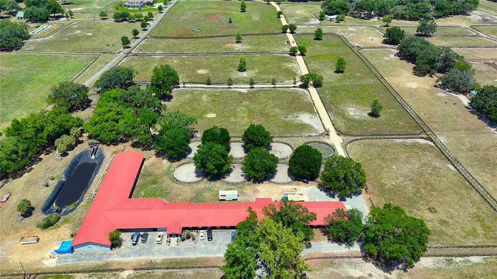 An aerial view shows a long red-roofed horse barn with adjacent paddocks and a pond — 6692 NW 150TH AVENUE, MORRISTON, FL