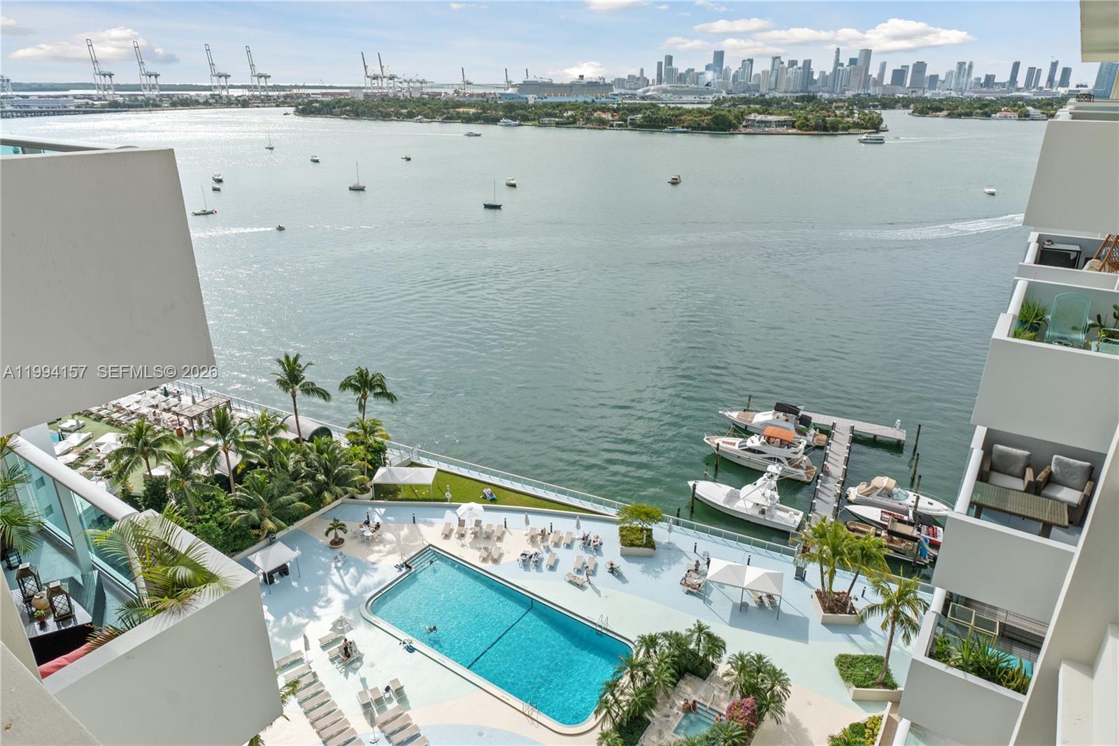 An elevated view of a swimming pool, boat dock, and bay with a city skyline — 1200 West Ave # 01, Miami Beach FL 33139, MIAMI BEACH, FL