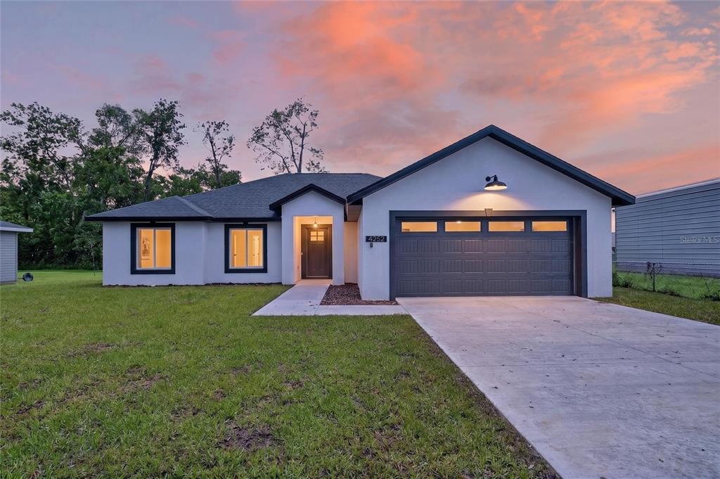 A single-story house with a white stucco exterior, dark trim, and an attached two-car garage — 4252 SE 135 LANE, SUMMERFIELD, FL