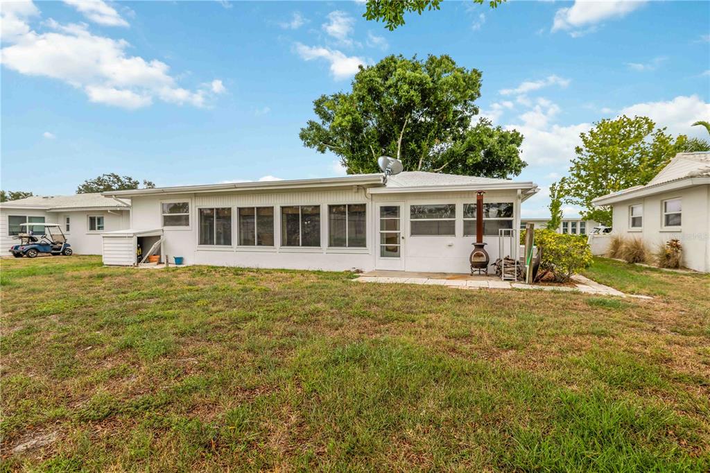 The exterior of a white house features a large enclosed sunroom and a grassy yard — 4001 CHINABERRY ROAD, BRADENTON, FL