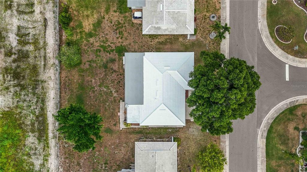 An aerial view shows a house with a white roof surrounded by trees and grass — 4001 CHINABERRY ROAD, BRADENTON, FL