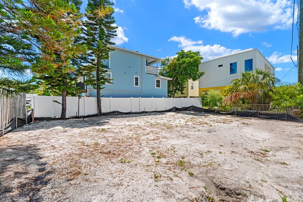 A vacant, sandy residential lot is enclosed by a white vinyl fence and nearby houses — 119 95TH AVENUE, TREASURE ISLAND, FL