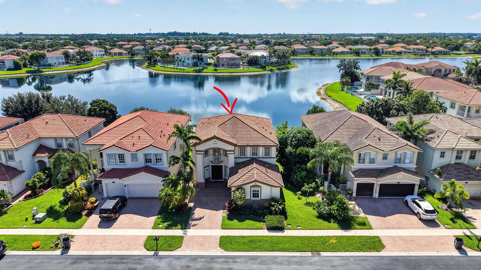An aerial view of a two-story house with a tiled roof facing a lake — 10675 Old Hammock Way, Wellington FL 33414, WELLINGTON, FL