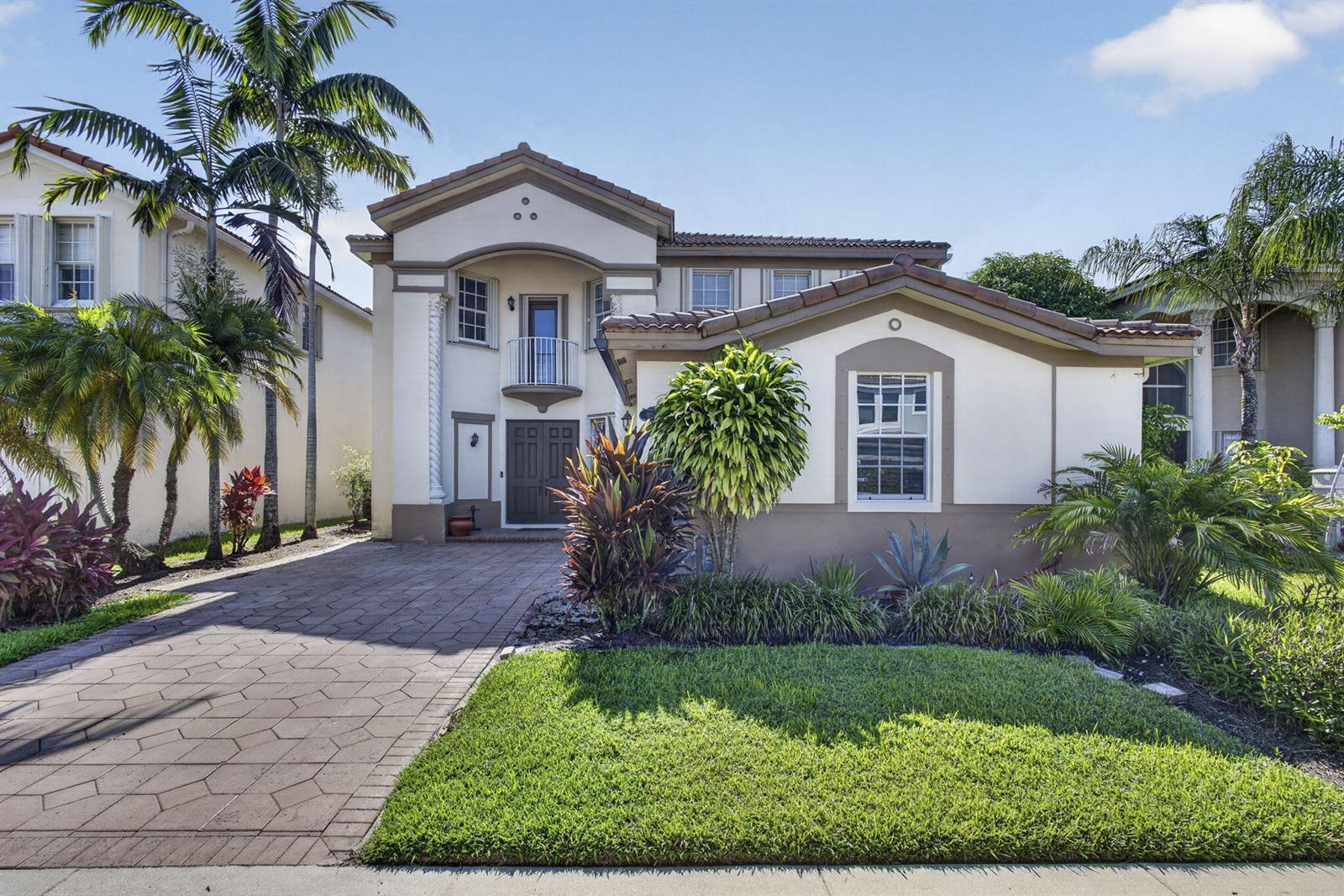 A two-story house with a paved driveway, a small balcony, and a landscaped front yard — 10675 Old Hammock Way, Wellington FL 33414, WELLINGTON, FL