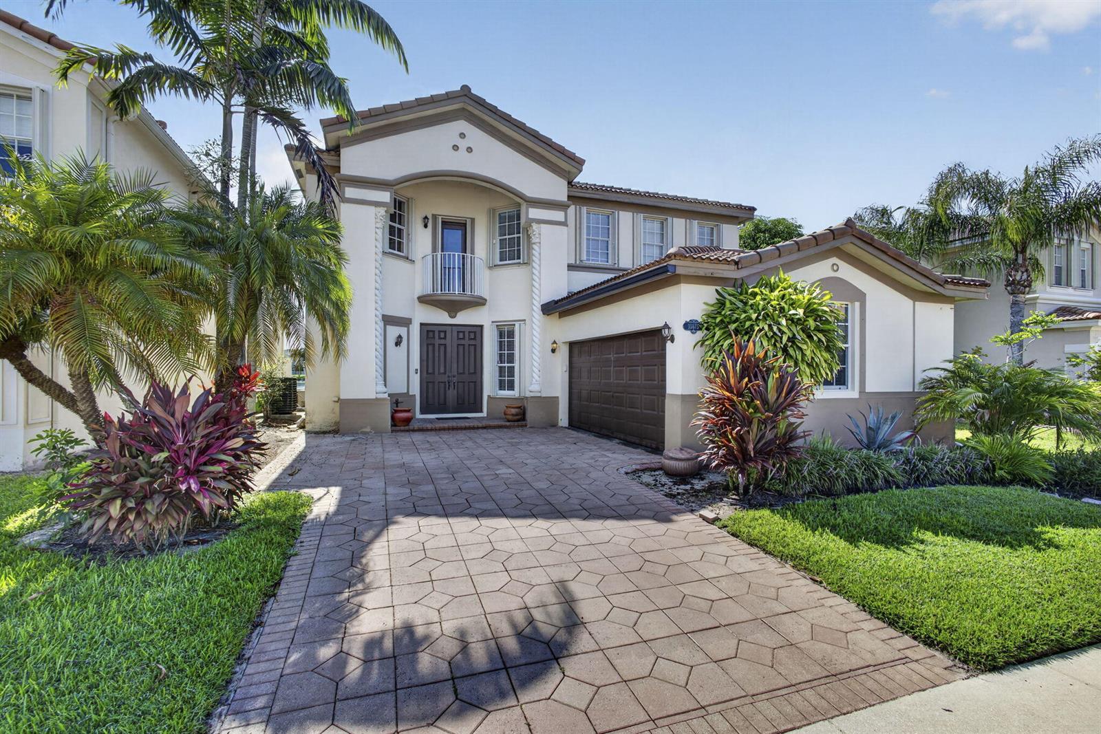 A two-story house with a paved driveway, a brown garage door, and a small balcony — 10675 Old Hammock Way, Wellington FL 33414, WELLINGTON, FL