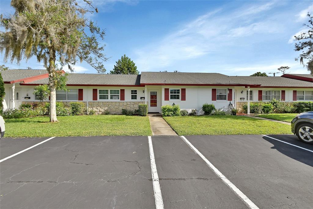 A single-story residential building with white siding, red shutters, and a stone facade base — 217 N HILL AVENUE UNIT 20, DELAND, FL