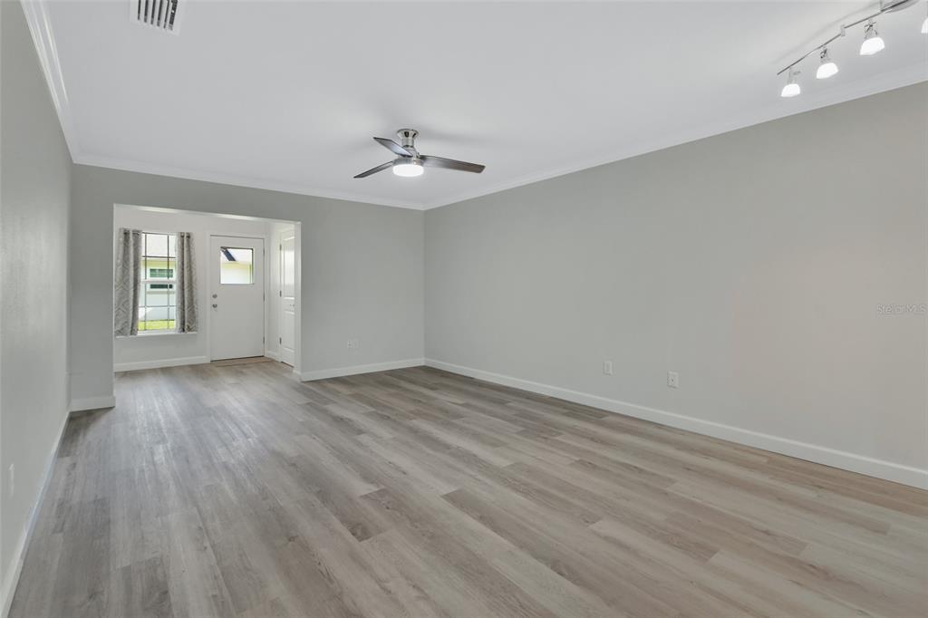 An empty living room features light gray walls, wood-look flooring, a ceiling fan, and track lighting — 217 N HILL AVENUE UNIT 20, DELAND, FL