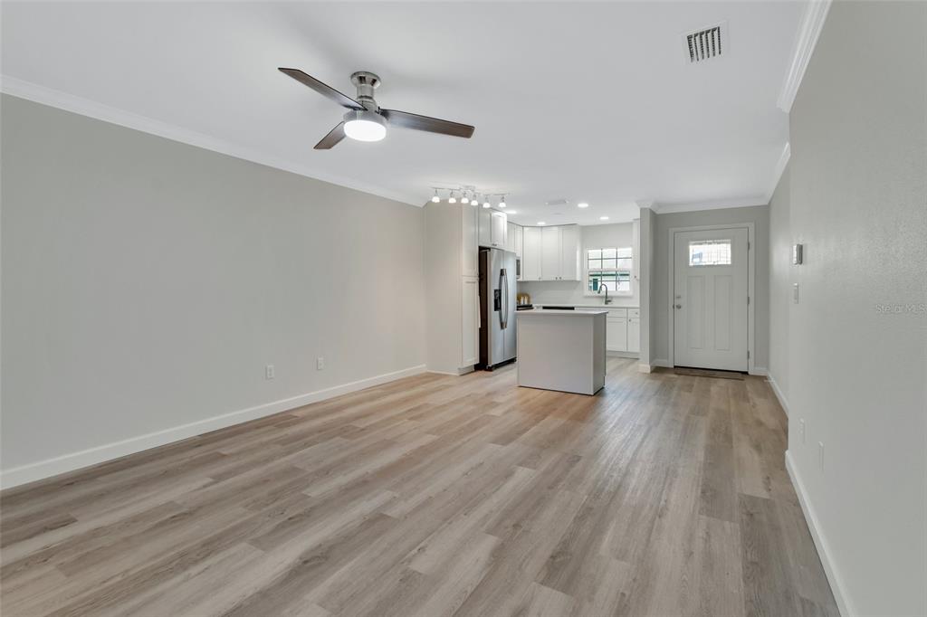 An open-concept kitchen and living area features light wood-look flooring, white cabinetry, and a ceiling fan — 217 N HILL AVENUE UNIT 20, DELAND, FL