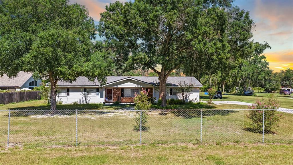 A single-story house with a white exterior and a chain-link fence in the front yard — 5604 WATSON ROAD, RIVERVIEW, FL