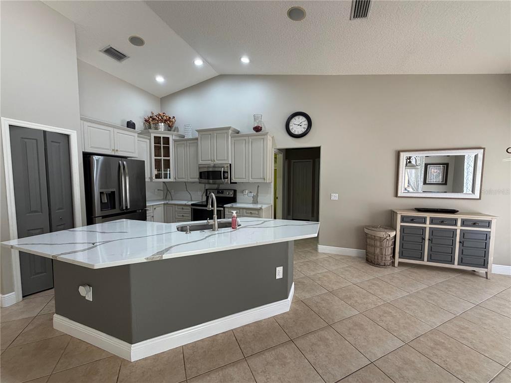 A kitchen features a large white quartz island, gray cabinets, and light-colored tile flooring — 9243 13TH AVENUE CIRCLE NW, BRADENTON, FL