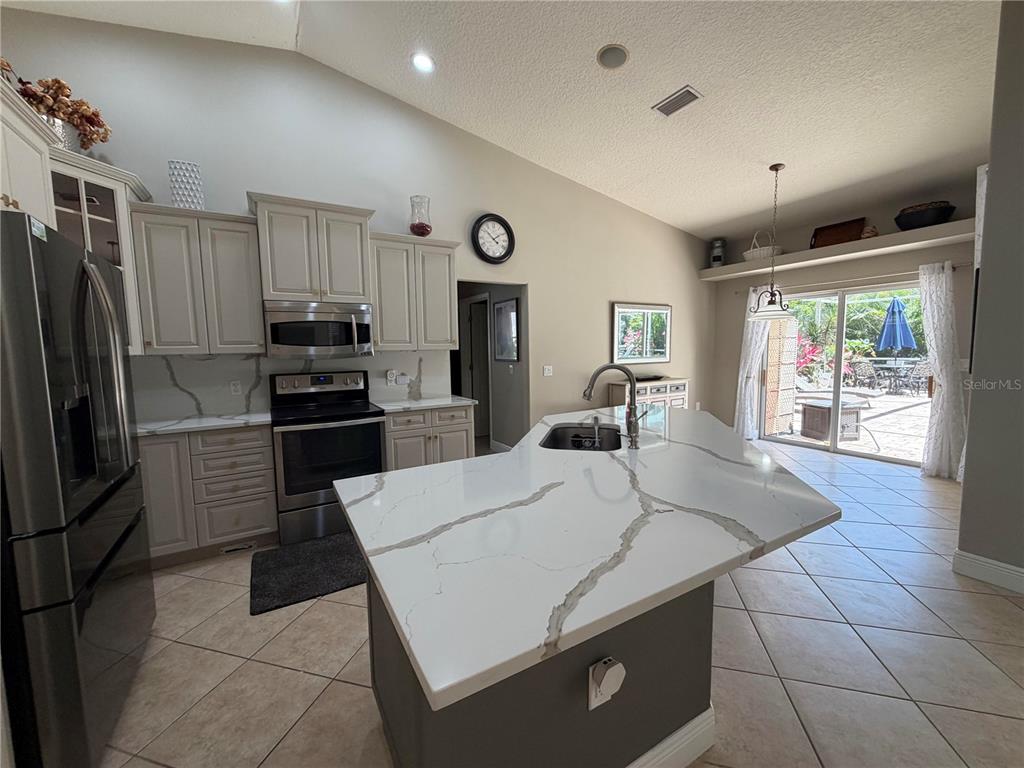 A kitchen with light-colored cabinets, a white quartz island, and a sliding glass door — 9243 13TH AVENUE CIRCLE NW, BRADENTON, FL