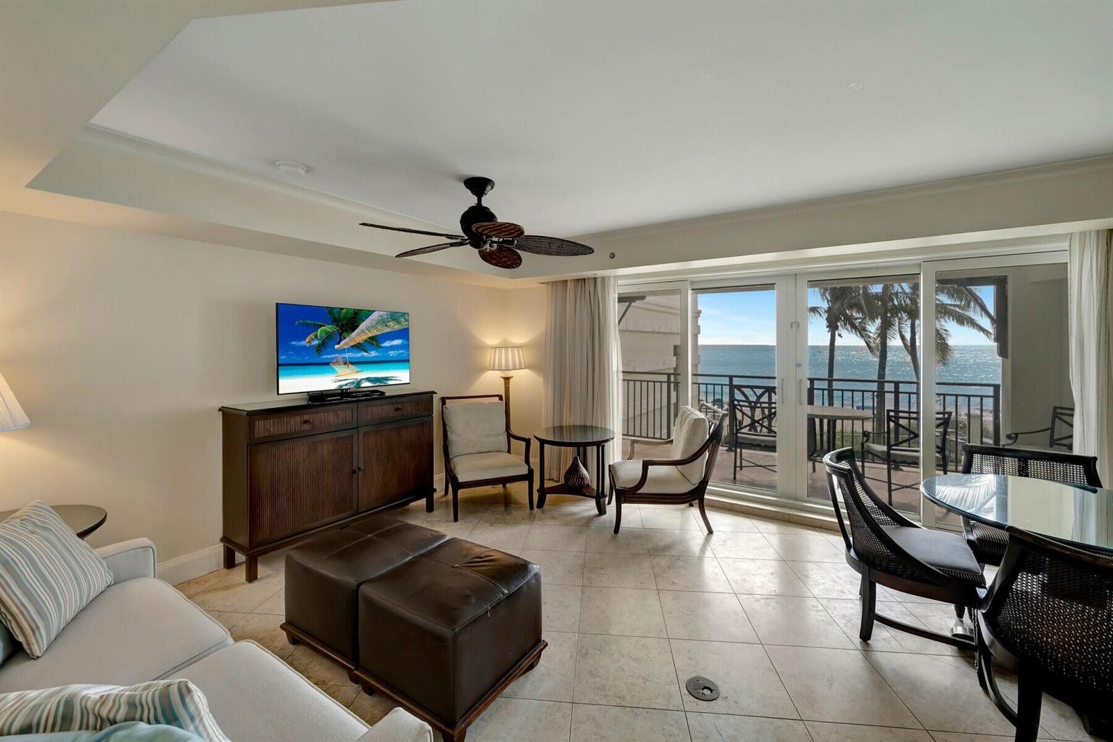 A living room with tile floors, a ceiling fan, and sliding doors opening to a balcony — 3500 Ocean Drive # 306, Vero Beach FL 32963, VERO BEACH, FL