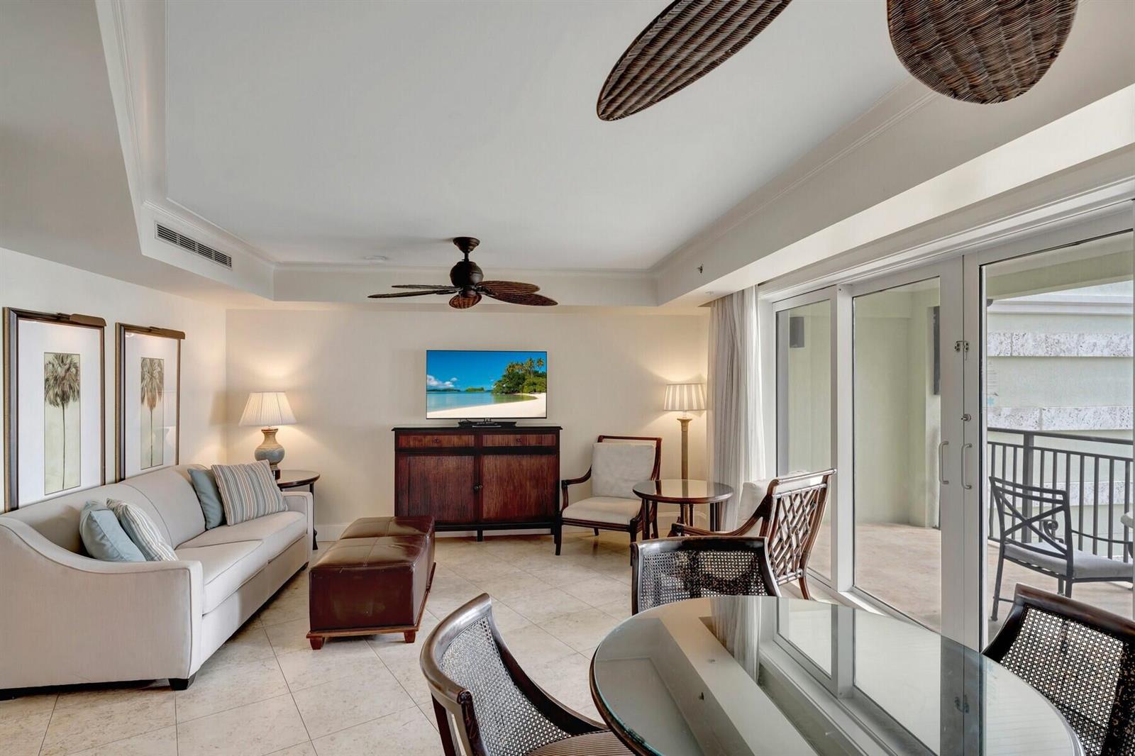 A living room features a sofa, television, dining area, and sliding doors to a balcony — 3500 Ocean Drive # 306, Vero Beach FL 32963, VERO BEACH, FL