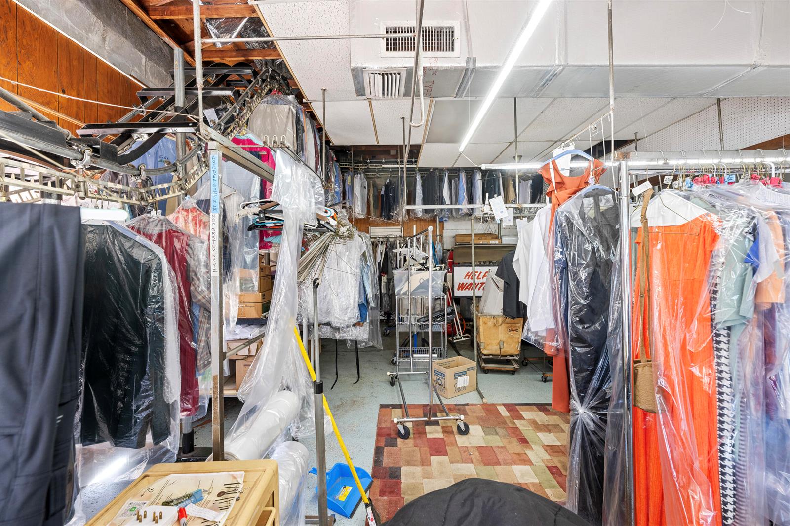 A dry cleaning facility features rows of hanging garments, industrial racks, and a tiled floor — 400 S Parrott Avenue, Okeechobee FL 34974, OKEECHOBEE, FL