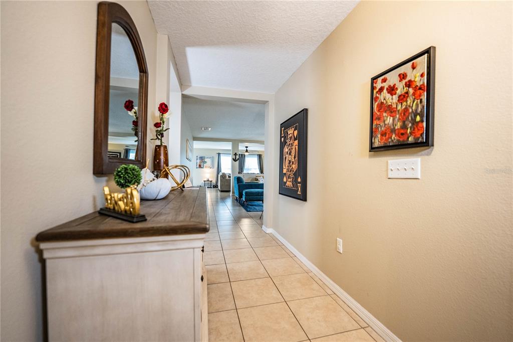 A hallway with tile flooring leads from a foyer toward a living area — 6015 CHAMPLAIN PASS, LAKELAND, FL