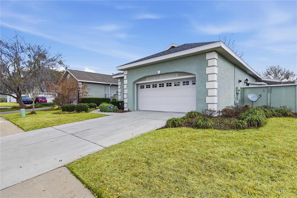 A light green house exterior features a two-car garage, a concrete driveway, and landscaped lawn — 4111 SW 30TH COURT, OCALA, FL