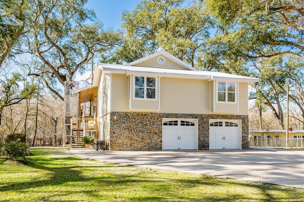 A two-story house with tan siding, a stone-faced ground level, and two white garage doors — 498 SW MANATEE TERRACE, FORT WHITE, FL